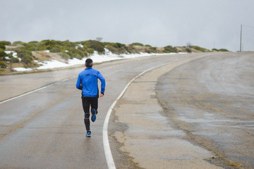 Athlete training and running in winter on mountain road