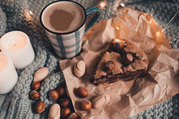 Homemade chocolate cake with nuts and cup of coffee in bed on knitted cloth close up. Good morning. Breakfast. Autumn season. Still life.