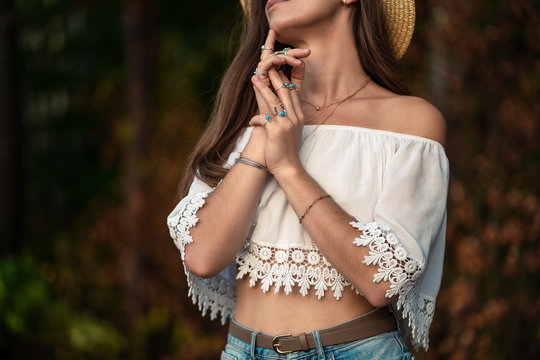 Beautiful fashionable boho chic woman in straw hat and in a white short blouse with silver turquoise jewelry. Boho fashion. Stylish girl with silver rings using hippie style.
