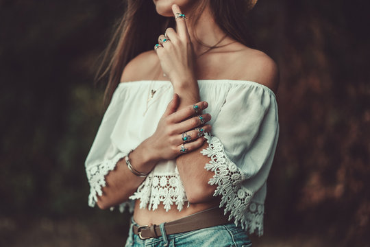 Fashionable brunette boho chic woman in a white short blouse and with silver turquoise jewelry. Boho fashion. Stylish girl wearing silver rings with turquoise stone in hippie style.
