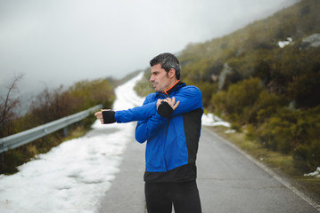 Runner training under snow on a mountain road in winter.