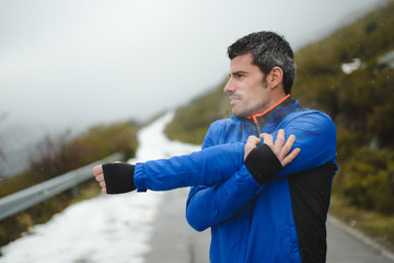 Runner training under snow on a mountain road in winter.