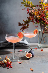 Pink cocktail with fig and basil on gray background close up. Autumn drinks