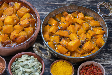 Baked yellow pumpkin with honey, anise, olive oil and spices on a plate on the wooden table. Vegetarian food. Closeup