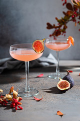 Pink fig martini cocktail in glasses on gray table. Autumn party