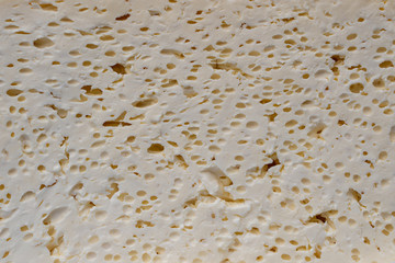 Hard cottage cheese cut in half with the texture of pulp. Cheese slices background, closeup