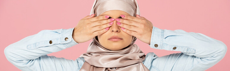 serious muslim girl in hijab closing eyes, isolated on pink
