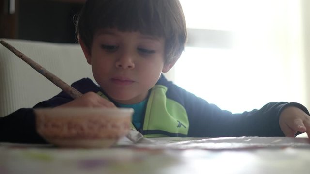little boy paints folio with brush impregnated with glue or paint