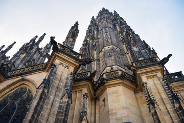 Fototapeta na wymiar View from below on tall ancient the St. Vitus Cathedral with statues in Prague