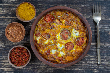 Ceramic bowl with vegetable frittata, simple vegetarian food. Frittata with tomato, pepper, onion and feta cheese on wooden table, close up. Italian egg omelette
