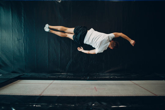 Young male acrobat jumping on a trampoline