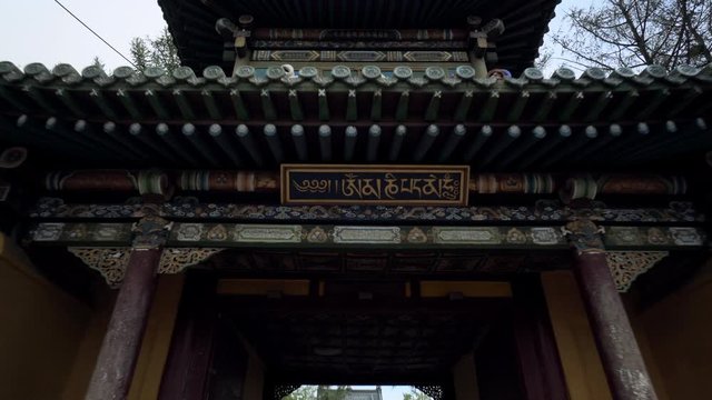 Tourists at Buddhist temple with non-western script on entrance in city against sky - Ulaanbaatar, Mongolia