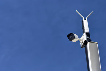 surveillance cameras and a warning system. CCTV cam on a pillar against blue sky