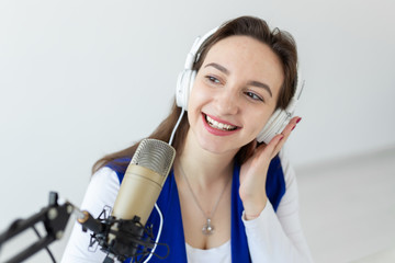 Radio host concept - Woman working as radio host sitting in front of microphone over white...