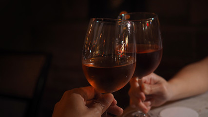 Closeup of male and female hands holding glasses of red wine. Selected focus.