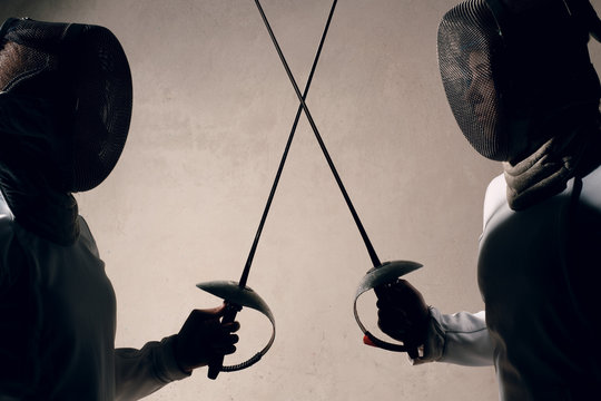 Fencer woman with fencing sword. Fencers duel concept.