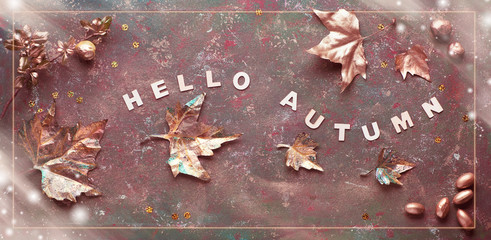 Autumn flat lay with painted golden leaves and text "Hello Autumn" on dark green textured bacgkrdound