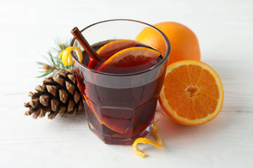 Glass of tasty mulled wine with orange on white wooden background, space for text