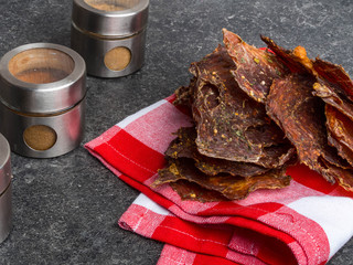 dried meat pieces, dehydrateed slices in spices, on the kitchen towel