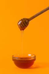A stick for honey and a small jar, concept on a yellow background.