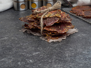 Dried meat slices with spices in jars, copy space