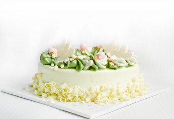 white chocolate birthday cake. is creamy, white and green, with beautiful spiral petals. On a white fabric background