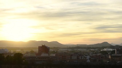 Dual carriageway and cityscape at sunset. Cars are in moved