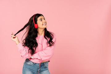 beautiful girl listening music with headphones, isolated on pink