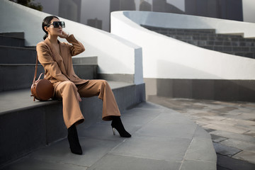 Portrait of a successful business woman sitting on stairs. City background