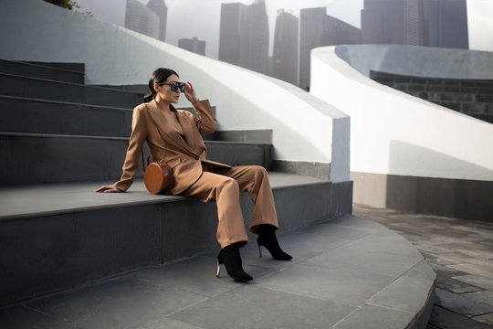 Portrait of a successful business woman sitting on stairs. City background