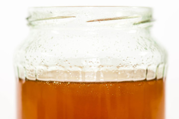 Jar filled with delicious bio honey close up shot on white background.