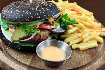 black burger with fries and sauce