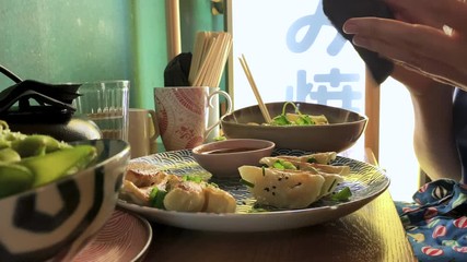 Woman eating delicious Jiaozi Gyoza Edamame and salads in Asian restaurant
