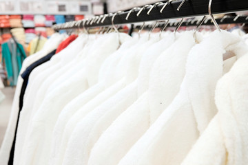 Bathrobes are white and colored for women and men, on hangers in the clothing store and textiles made of natural materials. The concept of seasonal sale