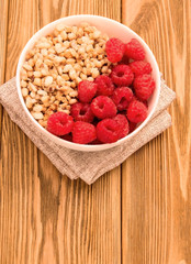 healthy breakfast raspberries and granola on a wooden table.
