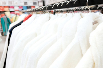 Bathrobes are white and colored for women and men, on hangers in the clothing store and textiles made of natural materials. The concept of seasonal sale