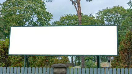 large long empty white billboard over wooden fence in city park on street, mock-up