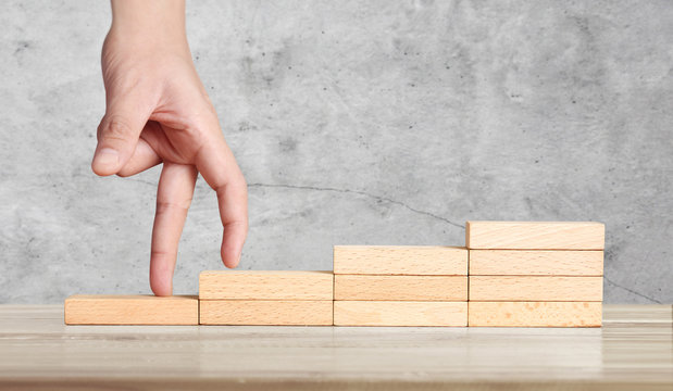 Hand liken person stepping up wood block stacking as step stair