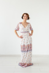 people, fashion and style concept - young woman posing in clothes in studio on white background