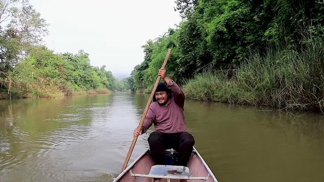Thai man rowing a river long boat at Chang Rai Northern Thailand