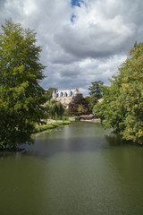 Fototapeta na wymiar La rivière Indrois entre ses rives bordées d'arbres et le nouveau château de Montrésor