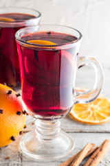 Glass of delicious mulled wine with oranges anise cinnamon on white wooden table