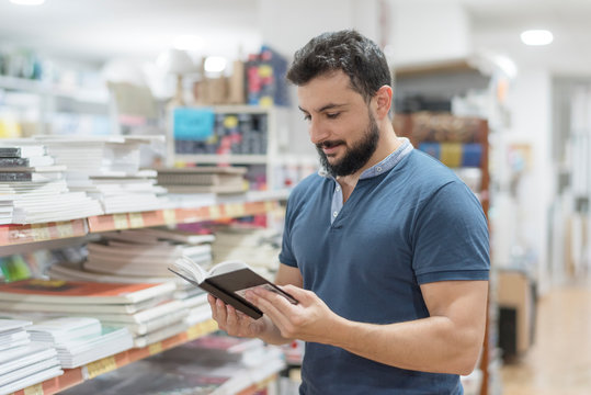 Bearded 35 Years Old Man Looking Book In Library And Crafts Store