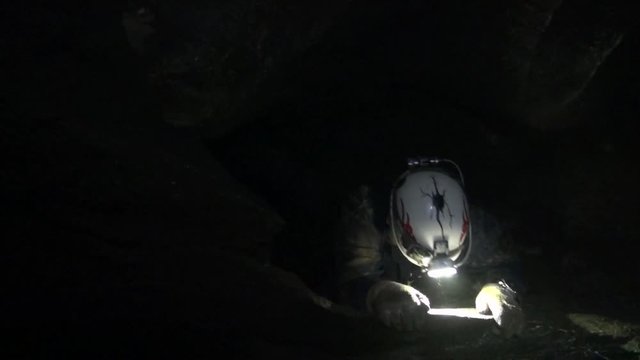 Caver struggles to pull himself up a steep slope