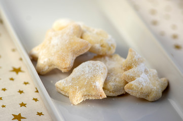 whipped cream delicious cookies with sugar icing on white ceramic plate, tablecloth with golden stars