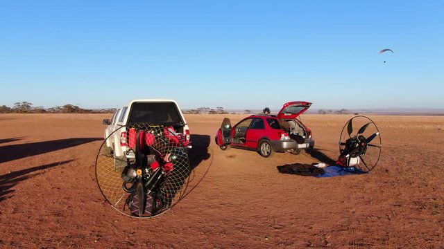 Preparing a Paramotor engine whilst a powered paraglider flies in the early hours in Outback Australia