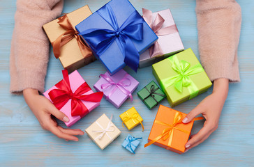 Multi-colored gift box with bow in woman's hands. Flatlay
