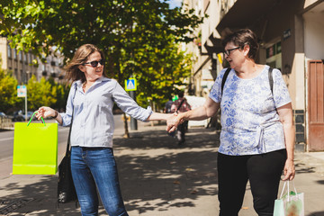 Happy mother and daughter holding bags going shopping in the city