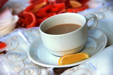 Cup of coffee milk, a bright yellow slice of marmalade on a saucer