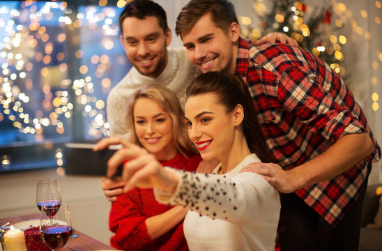 holidays and celebration concept - happy friends taking selfie by smartphone at home christmas dinner